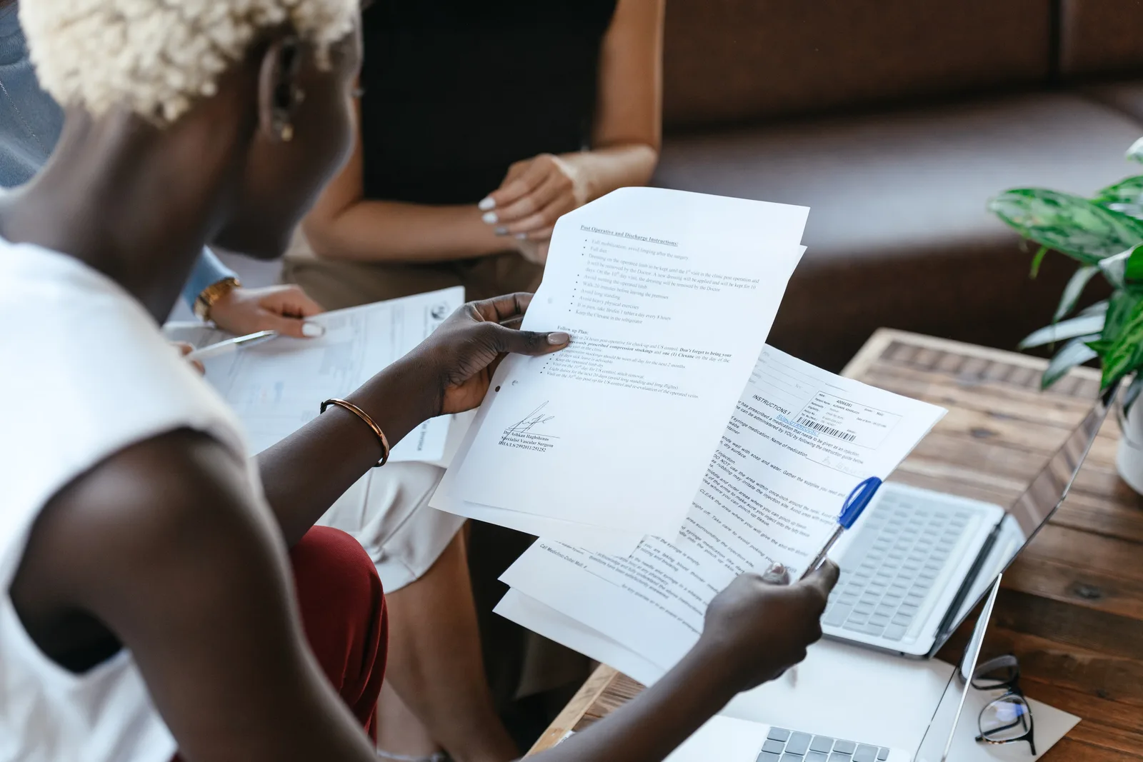 From above of crop anonymous African American female comparing data in papers at table of office