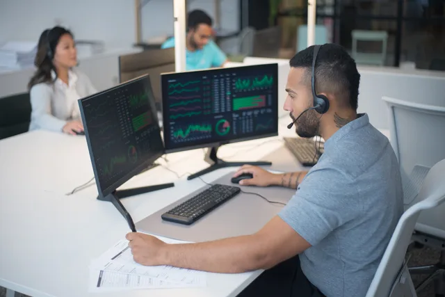 Team of customer service professionals working with headsets and computers in a modern office. How to choose a customer success software channel strategy