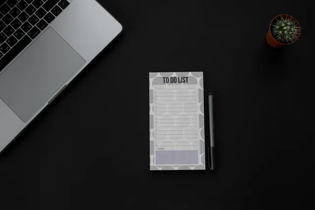 A minimalistic desk setup featuring a laptop, to-do list, and pen on a dark background. Ideal for productivity themes. Map customer success software data protection duties before you sign