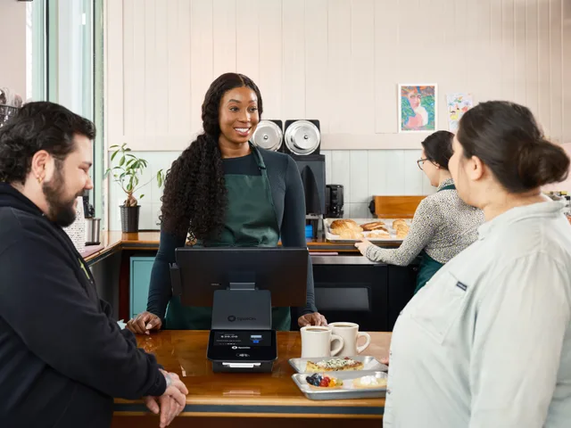A friendly barista assists customers at a modern cafe with advanced POS technology. Writing a customer success software disclosure policy without overpromising