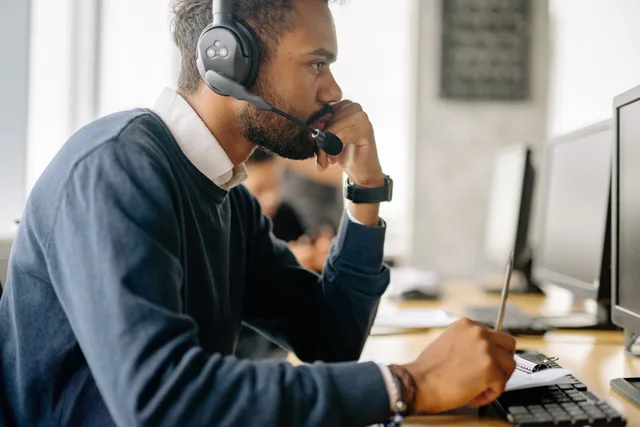 Side view of a bearded man in a headset concentrating at his desk in an office environment. Checks to run before planning customer success software market entry