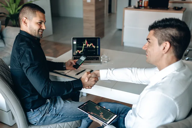 Two businessmen shake hands over a successful stock trading agreement using technology in a modern office. How to build a customer success software outlook