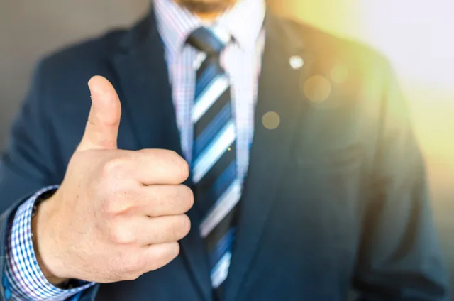 Close-up of a businessman in a suit giving a thumbs-up in a bright, positive setting. What a customer success software ninety day plan means for retention teams