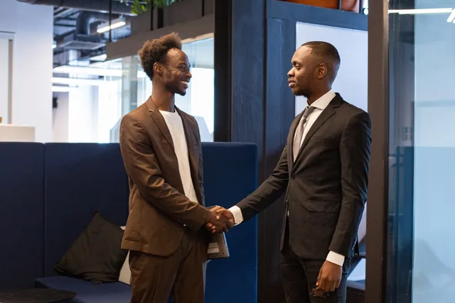 Two professional men shaking hands in a modern office setting, symbolizing successful business collaboration. How customer success software operations turn retention targets into daily delivery