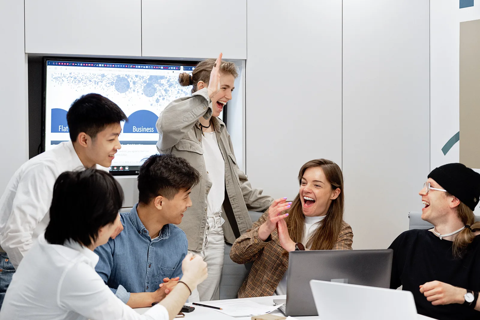 A diverse group of professionals celebrating a successful project in a modern office setting.