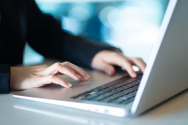 Close-up of hands typing on a laptop in a bright, modern office, symbolizing productivity and digital work. What supplier comparison means for customer success software buyers