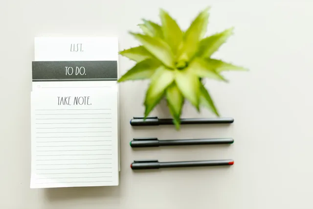 Flat lay view of a to-do list, black pens, and a potted plant for productivity inspiration. Customer success software vendor due diligence without the guesswork
